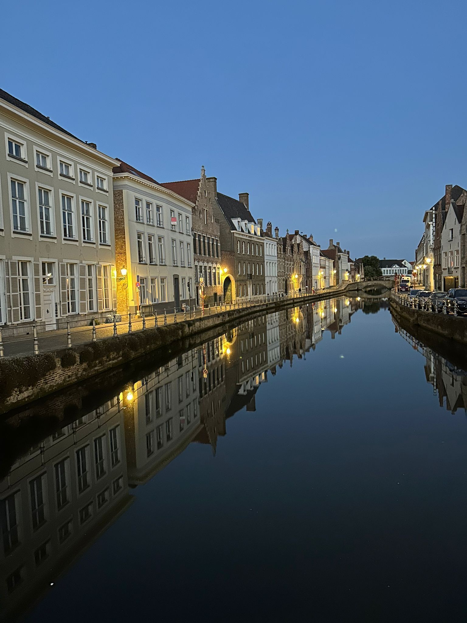 A canal with buildings on either side, a bridge, and a reflection in the water.