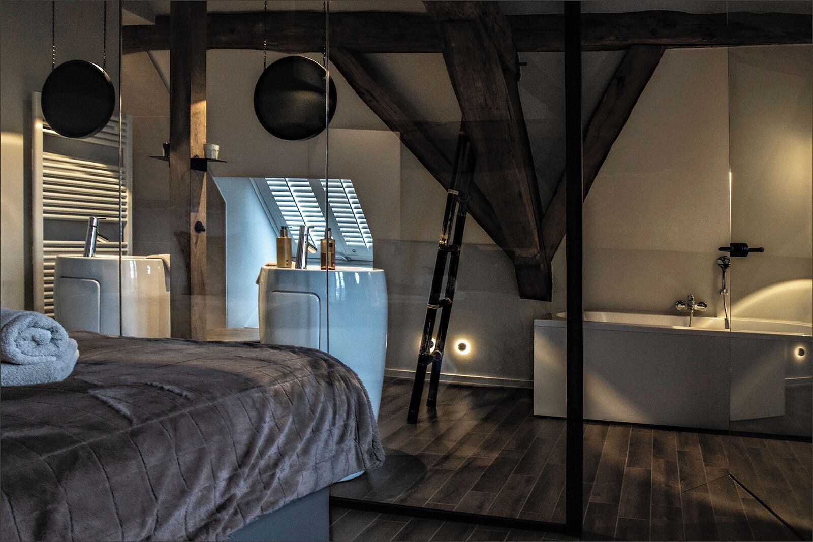 A modern bedroom with a large bed, a bathroom with a bathtub, and a skylight.