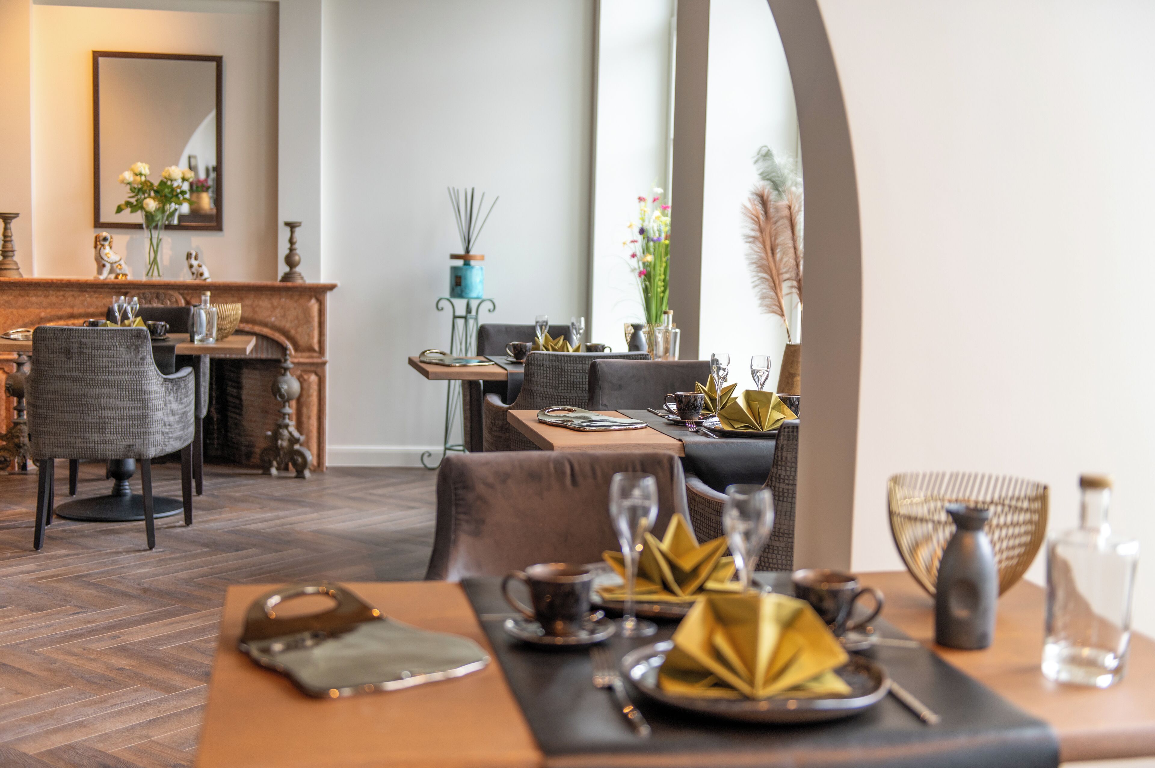 A dining area with a wooden table set for two, a fireplace, and a view of the cityscape through large windows.