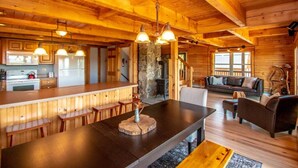 A wooden cabin interior with a kitchen, dining area, and living room. - Spacious Log Home Overlooking 40 White Mnt Peaks with Extreme Privacy: Host Weddings (Brownfield)