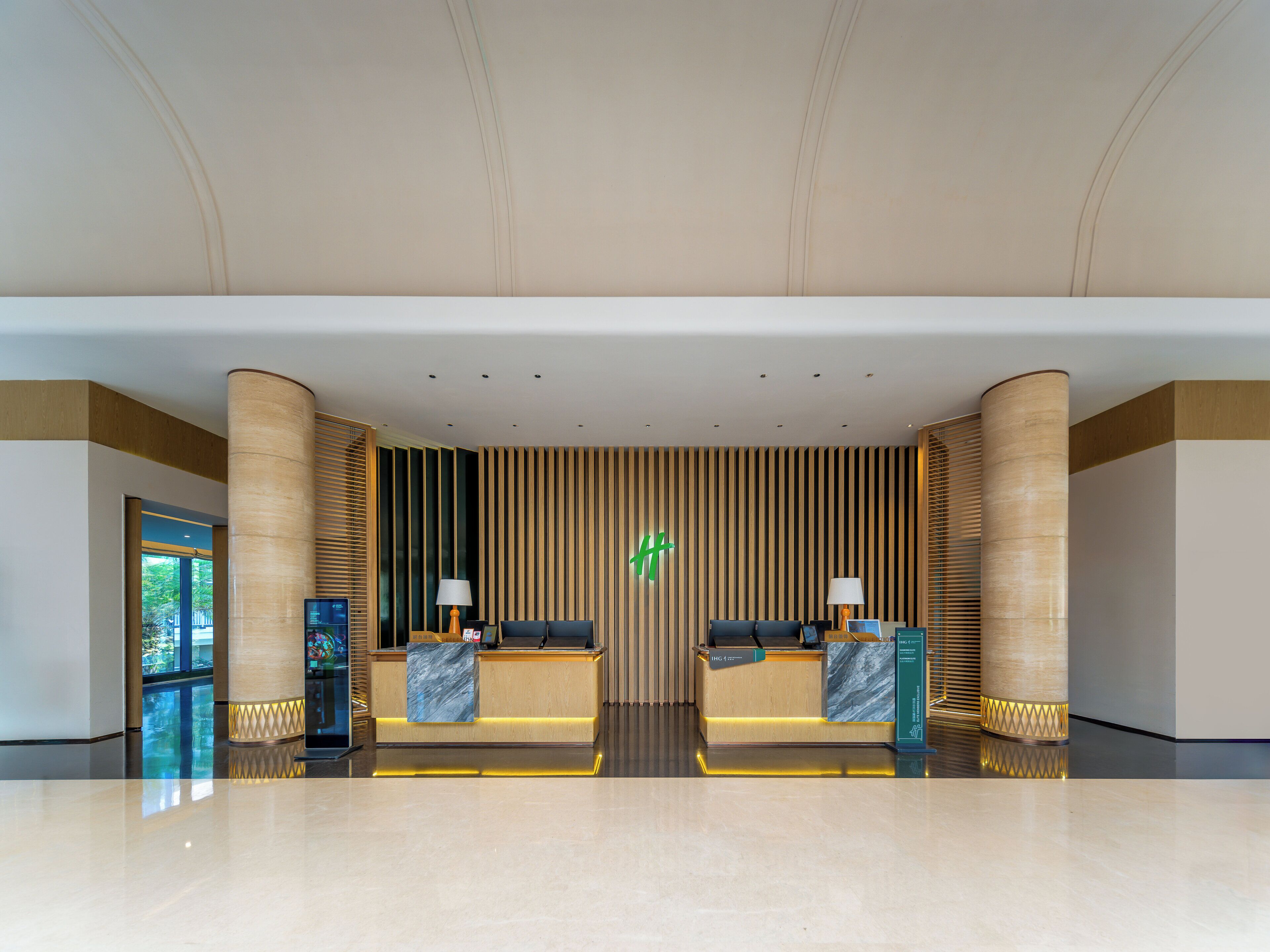 A modern lobby with a reception desk, seating area, and a large window.