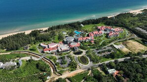 Ein Luftbild eines Resorts mit Strand, Schwimmbad und mehreren Gebäuden mit roten Dächern.