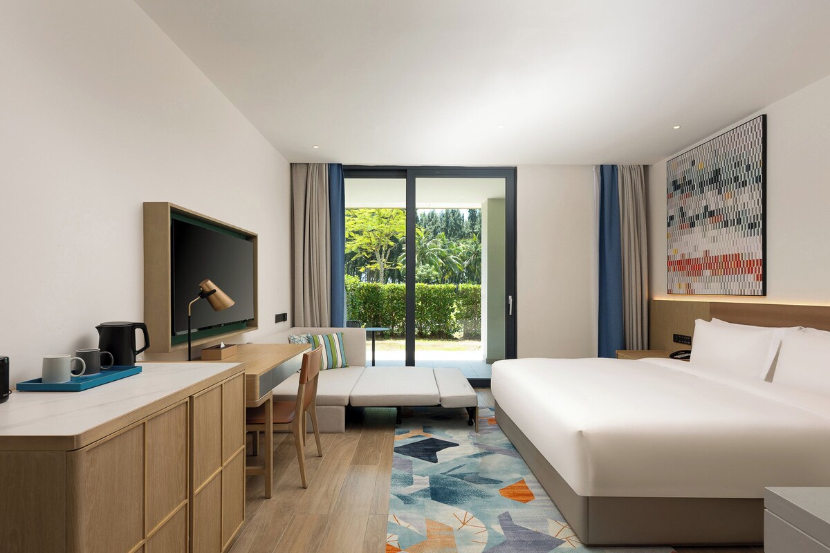 Een hotelkamer met een bed, bureau, stoel en een televisie.