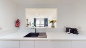 Een moderne keuken met een grote spoelbak, een koffiezetapparaat en een brandblusser.