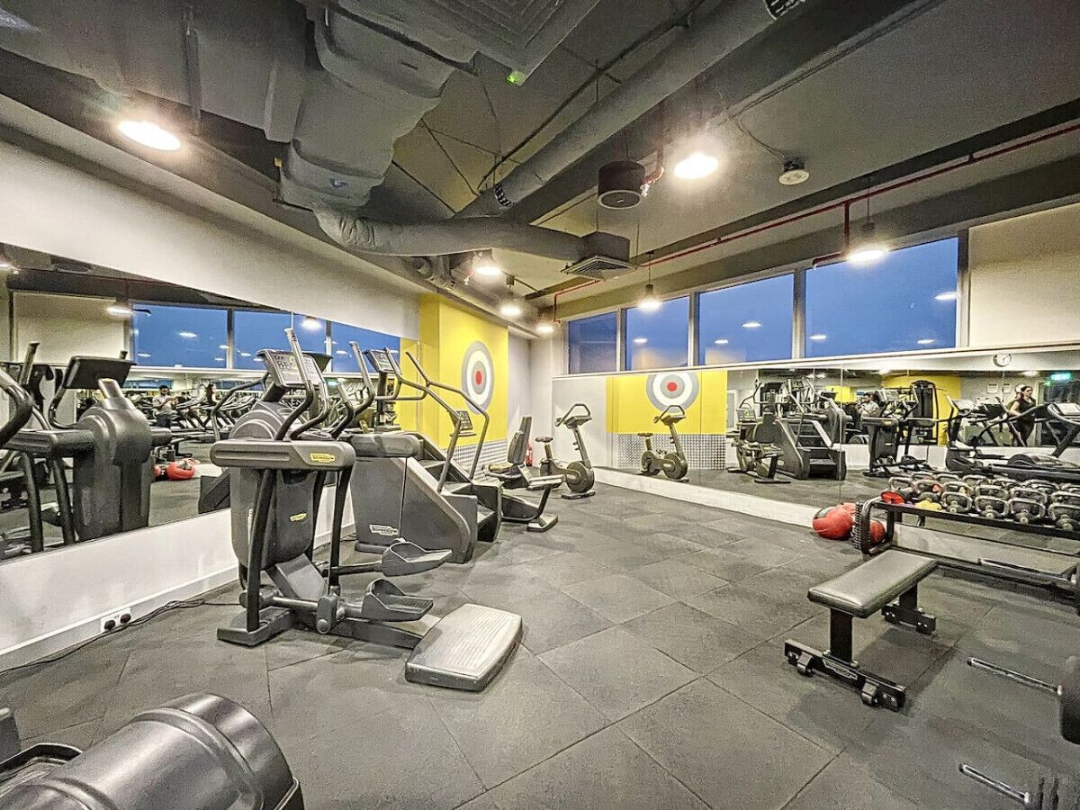 A gym with various exercise equipment, large windows, and a tiled floor.
