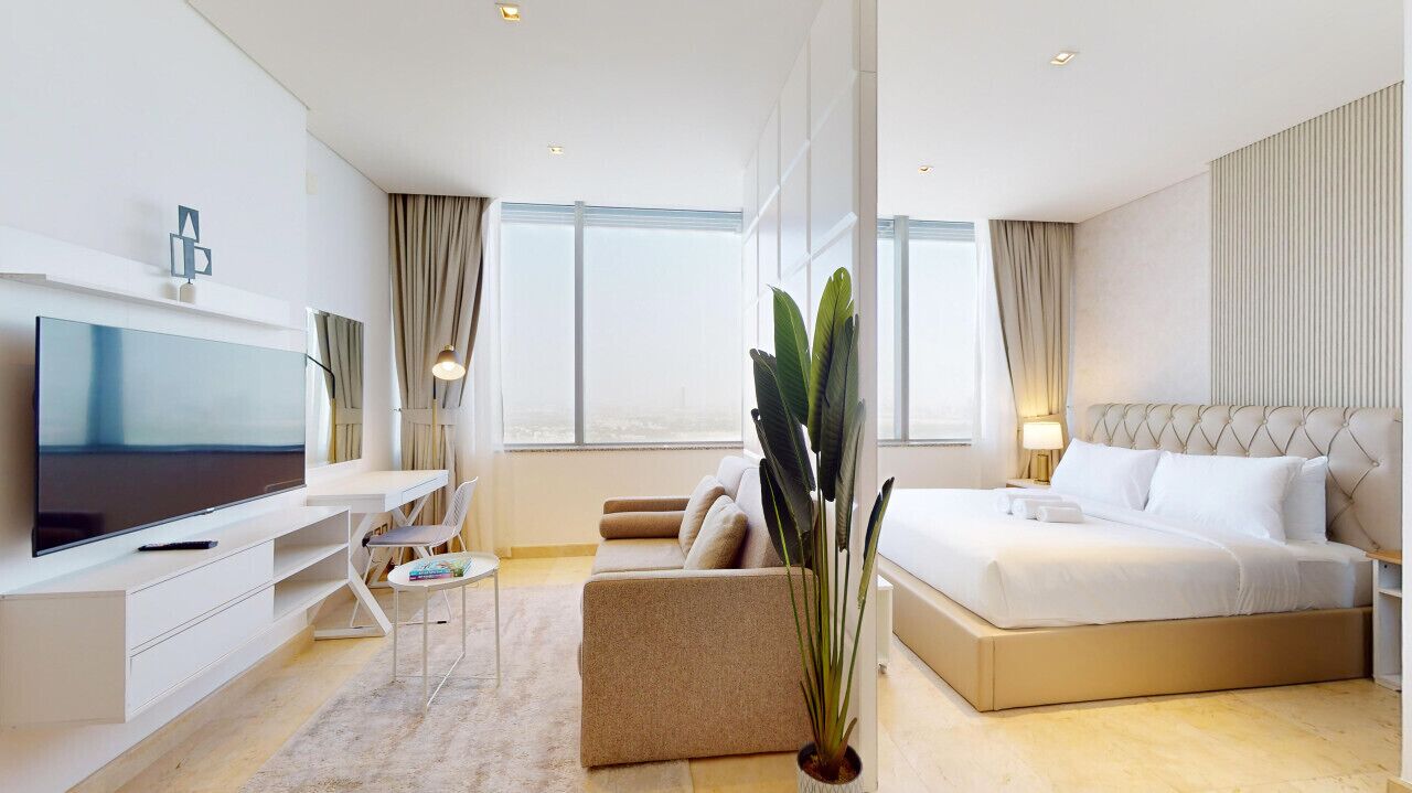 Une chambre d’hôtel moderne dotée d’un grand lit, d’un bureau avec un téléviseur à écran plat, d’un canapé confortable et de grandes fenêtres offrant une vue sur la ville.