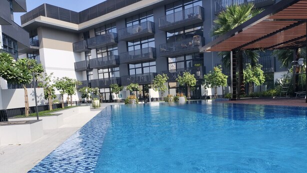 Un hôtel moderne doté d’une grande piscine, de nombreux balcons et d’un espace abrité agrémenté de palmiers.