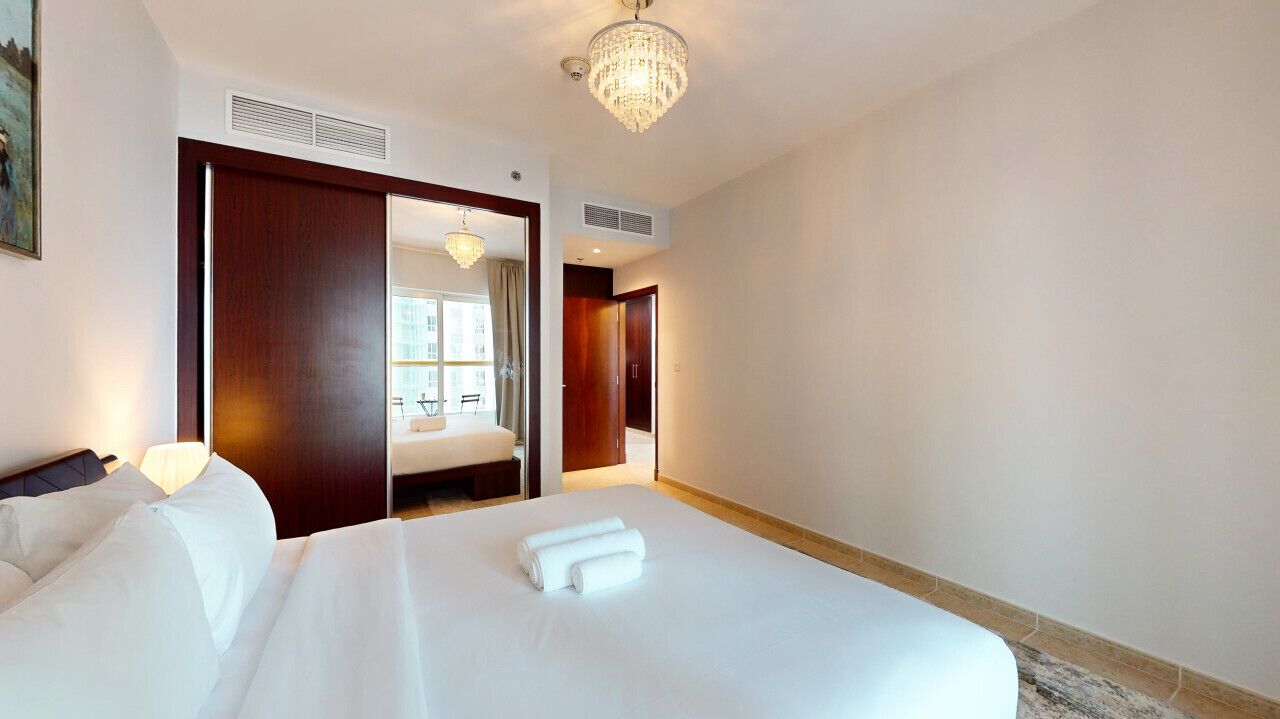 Ein Hotelzimmer mit einem großen Bett, einem Kleiderschrank, einer Chandelier und Blick ins Zimmerinnere.
