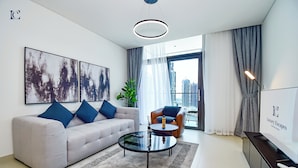 A modern living room with a sofa, coffee table, and a view of the cityscape. - 2bedroom Apt in Burj Crown (Dubai)