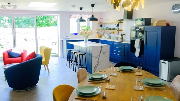 A modern kitchen with blue cabinets, a marble island, and bar stools. - Wave Cottage Bristol (Bristol)