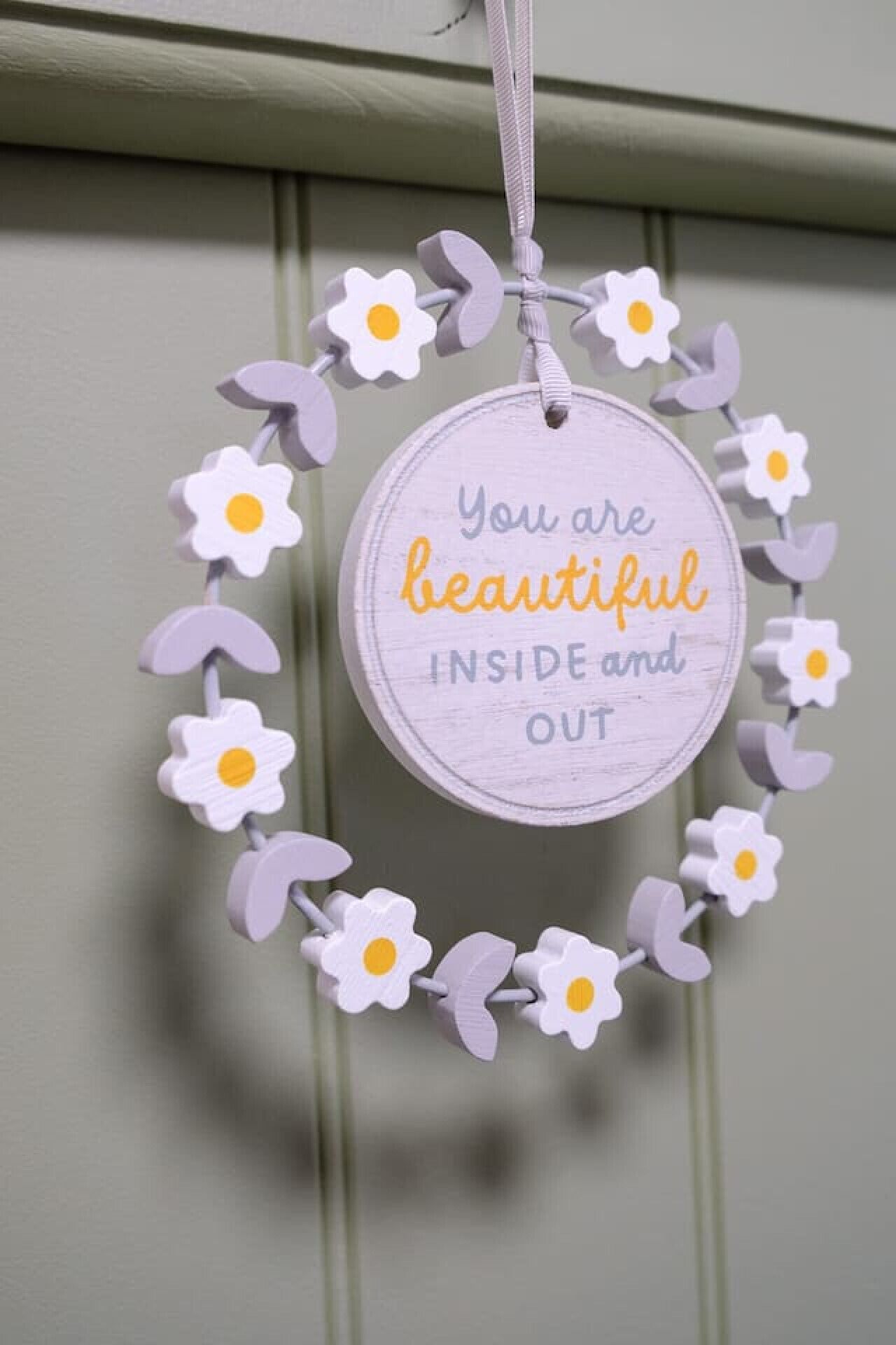 A circular wall hanging with a message and flowers.