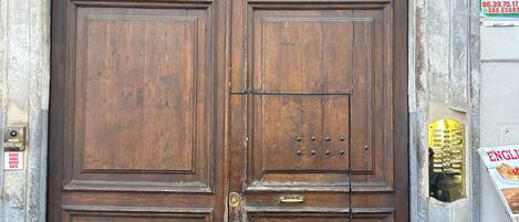 A large wooden double door with a brass handle and a small brass plate above it.