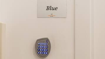 Cerradura electrónica con teclado en una puerta, con un cartel encima que dice 'Blue Urban Vatican ROOMS'.