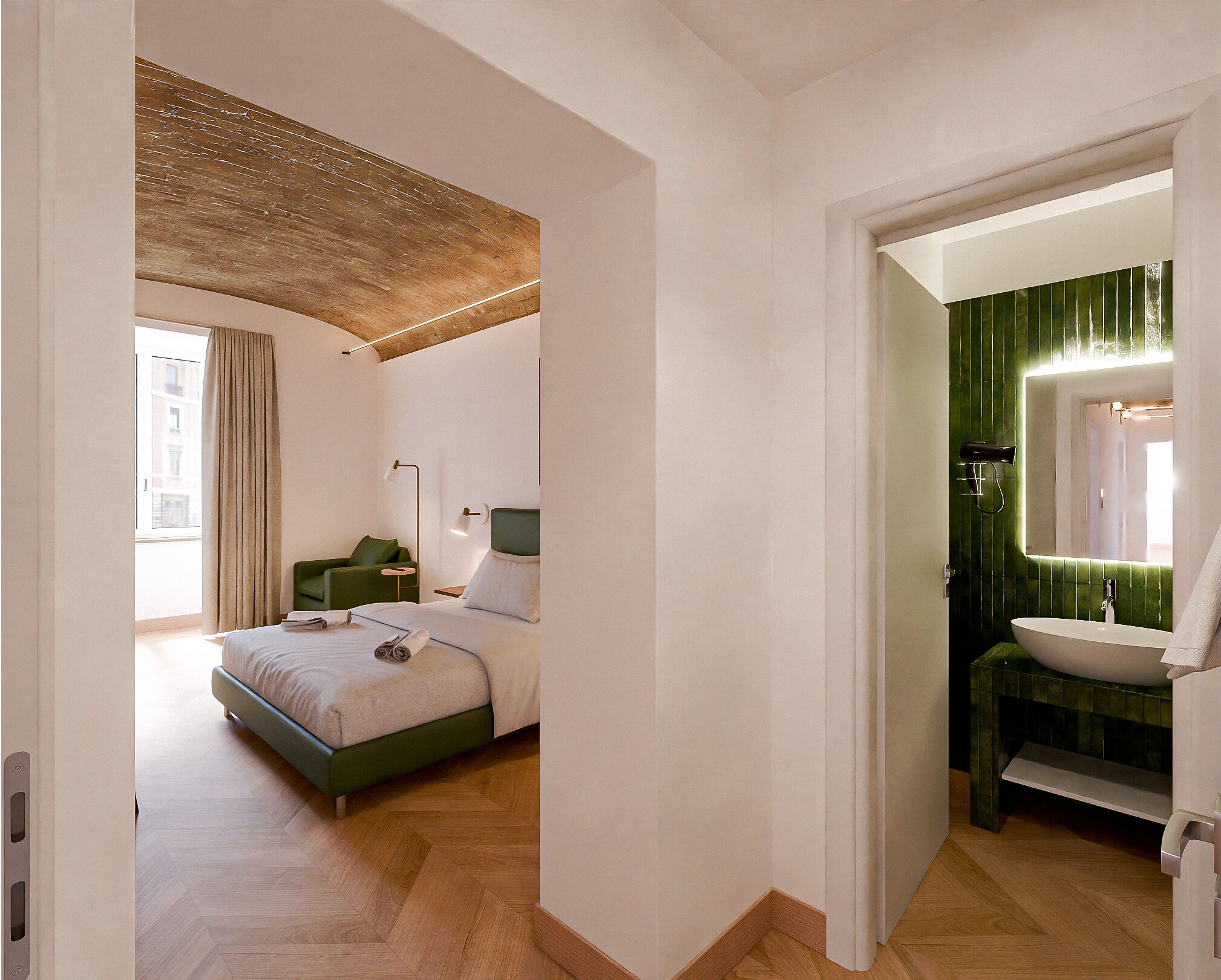 A modern hotel room with a bed, a desk, and a bathroom with a green wall and a white sink.