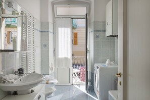 A bathroom with a sink, toilet, and washing machine.