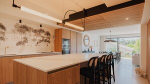 A modern kitchen with a central island, wooden cabinetry, and a dining area with bar stools. - Villa with private heated pool by the sea in Royan (Royan)