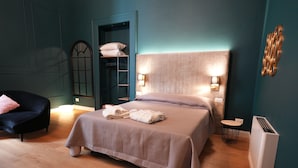 A bedroom with a large bed, a chair, a wardrobe, and a radiator.
