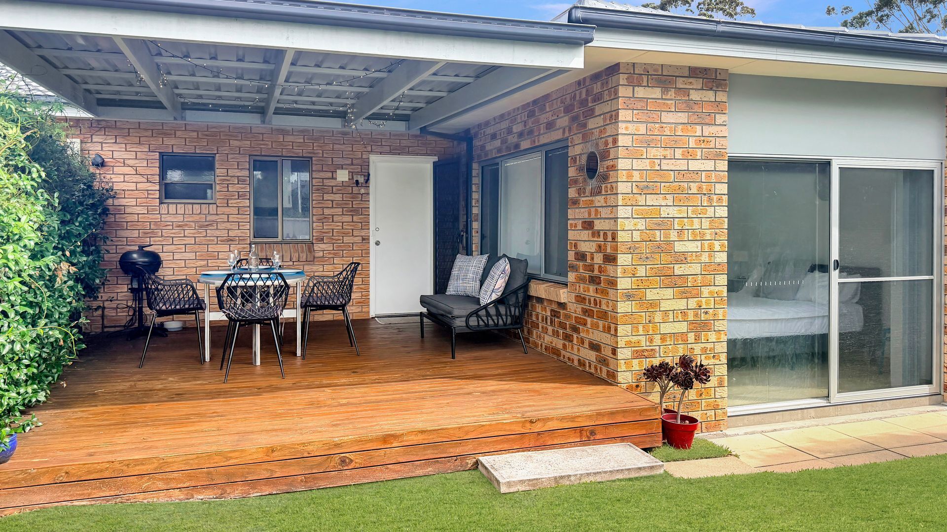Eine Terrasse mit Holzdeck, einem Tisch und Stühlen sowie einer Ziegelwand.