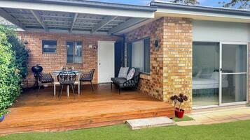 A patio with a wooden deck, a table with chairs, and a brick wall.