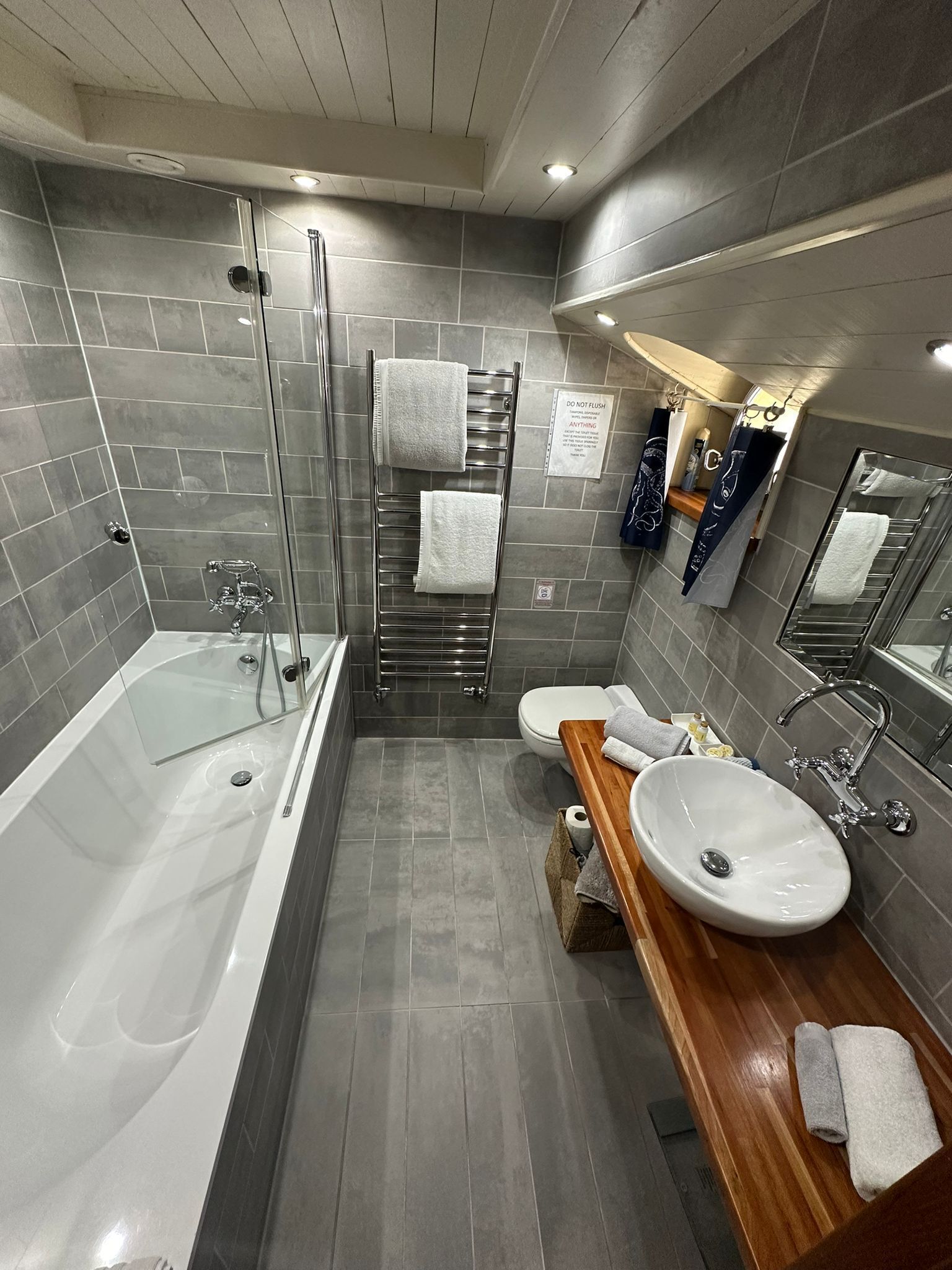A modern bathroom with a glass-enclosed shower, a wooden vanity with a sink, and a toilet.