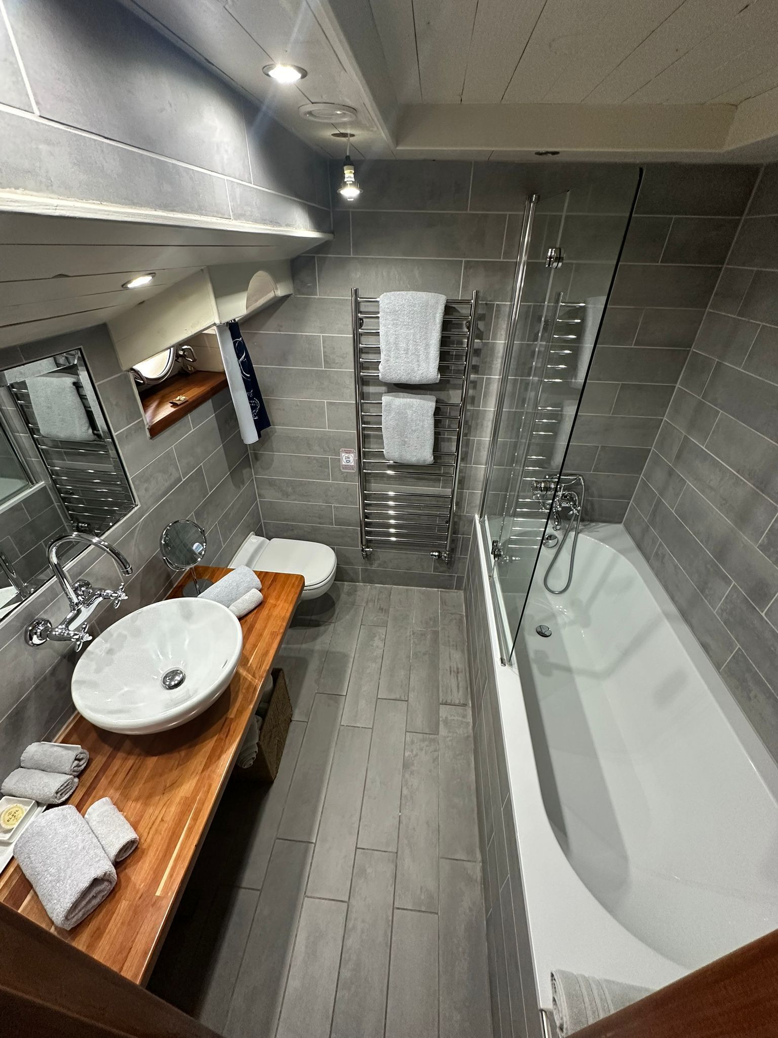 A modern bathroom with a large bathtub, two sinks, a glass shower enclosure, and a towel rack.