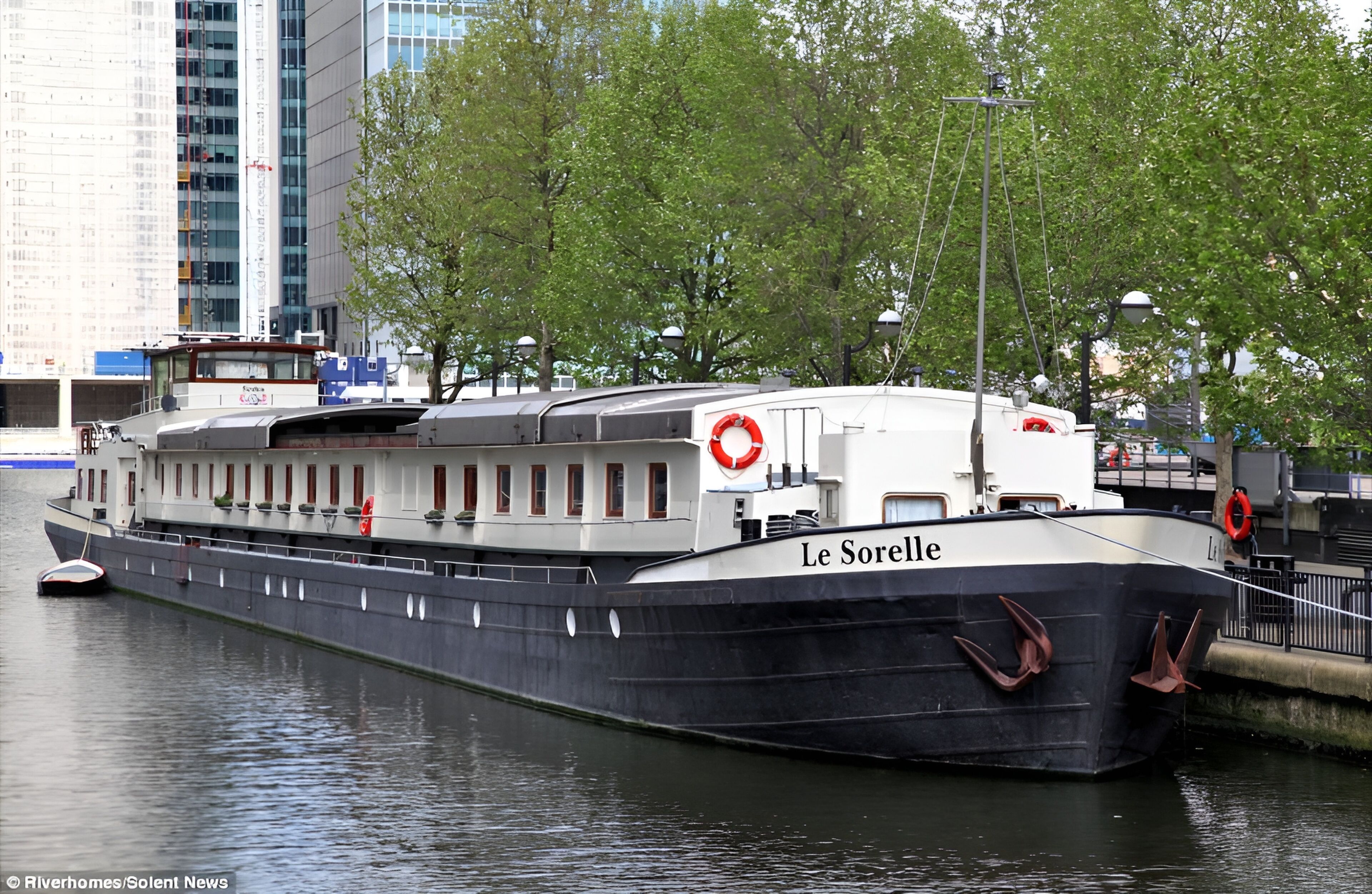 A large, stationary boat named 'Le Sorelle' docked at a port with a cityscape in the background.