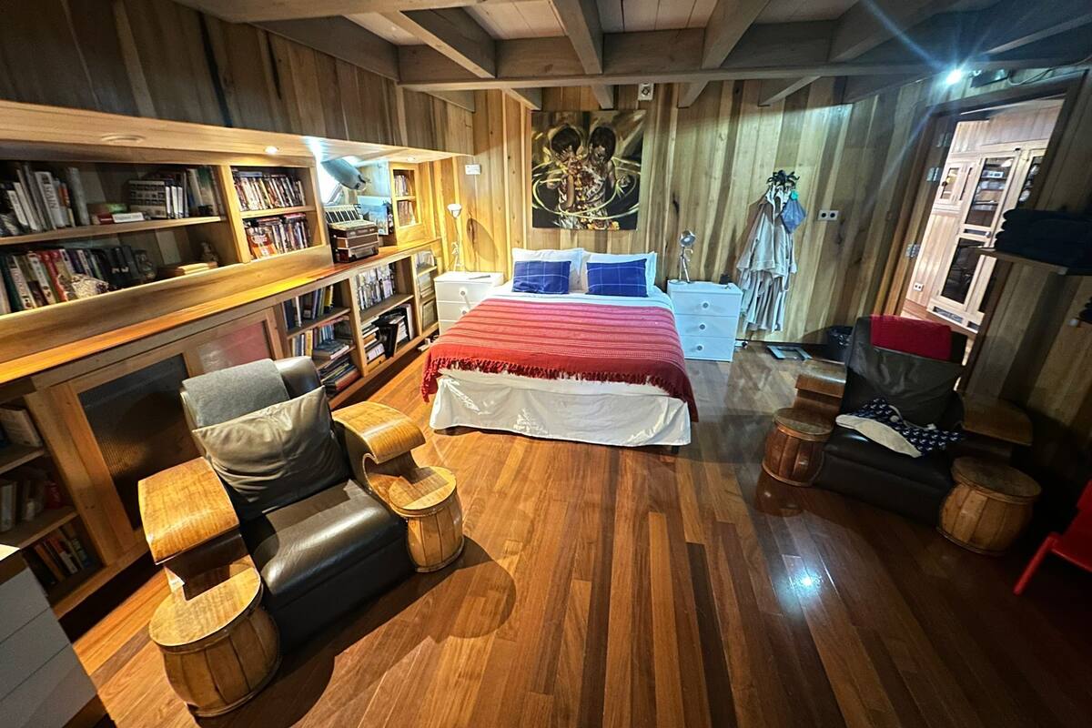 Una habitación acogedora con una cama grande, estanterías de madera, un escritorio y una silla.