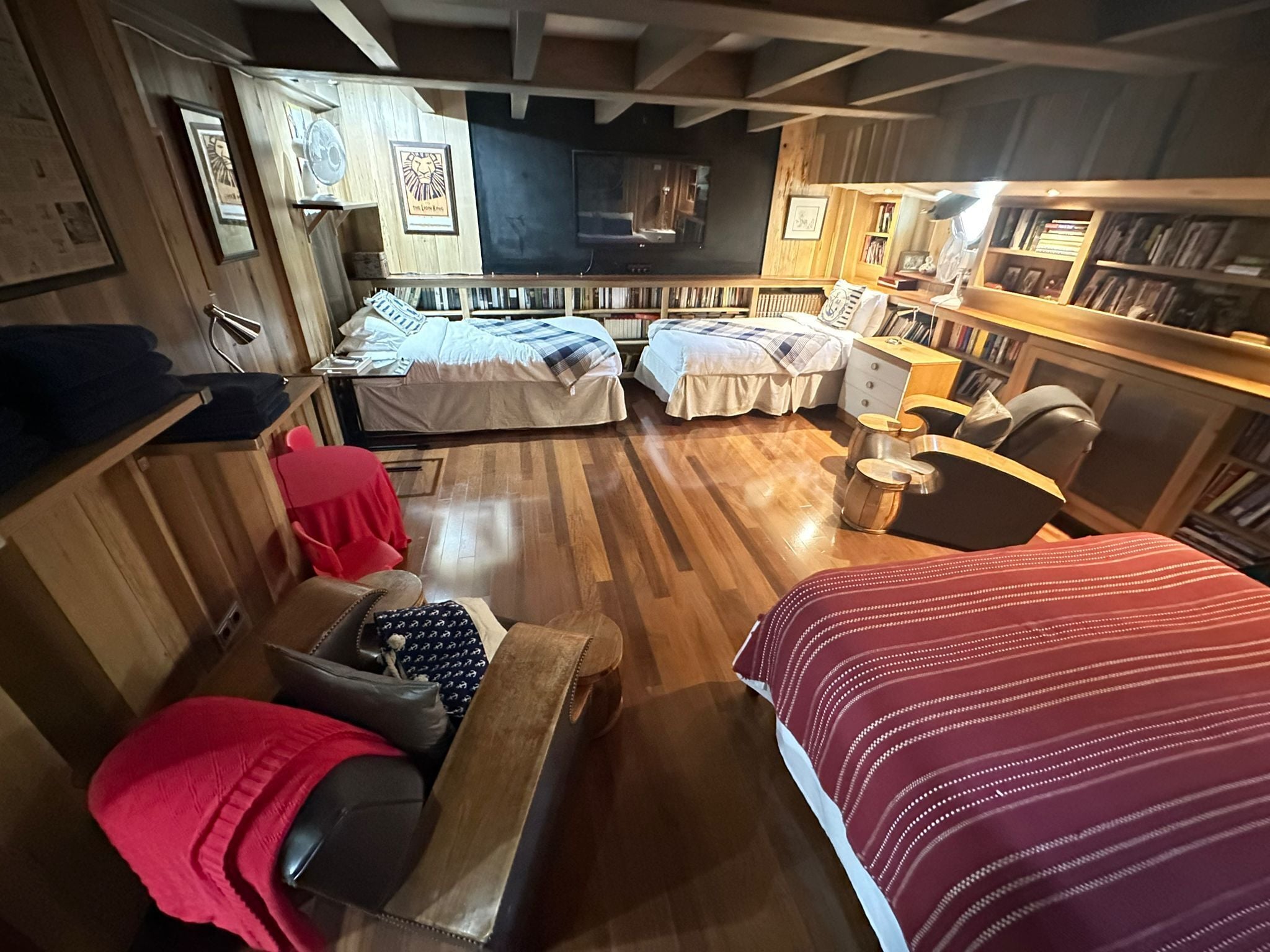 A cozy room with a wooden floor, two beds, a desk, and a bookshelf.