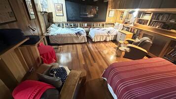 A cozy room with a wooden floor, two beds, a desk, and a bookshelf.