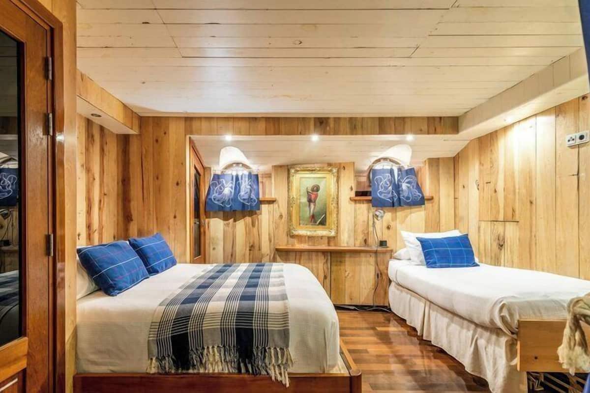 Una habitación tipo cabaña de madera con dos camas, un cuadro en la pared y techo de madera.