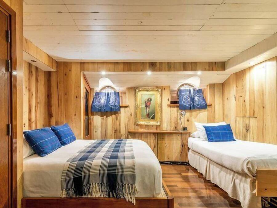 Une pièce aménagée comme un chalet en bois, avec deux lits, un tableau encadré au mur et un plafond en bois.