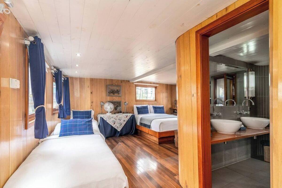Una habitación tipo cabaña con dos camas, techo de madera y baño con un espejo grande y dos lavamanos.