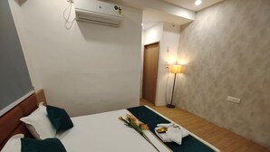 Een hotelkamer met een bed, kussens, een nachtkastje met een lamp en een airconditioner aan de muur.