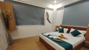 Een hotelkamer met een bed, houten vloer en een raam met jaloezieën.