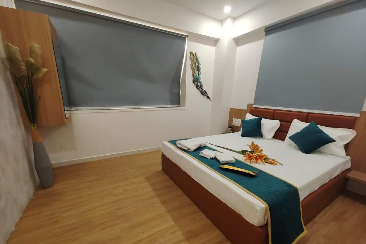 Une chambre d’hôtel avec un lit, un plancher en bois et une fenêtre avec des stores.