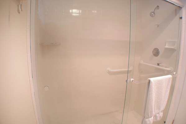 Une cabine de douche ferm ée par des parois en verre, avec une serviette blanche suspendue à un porte-serviettes.