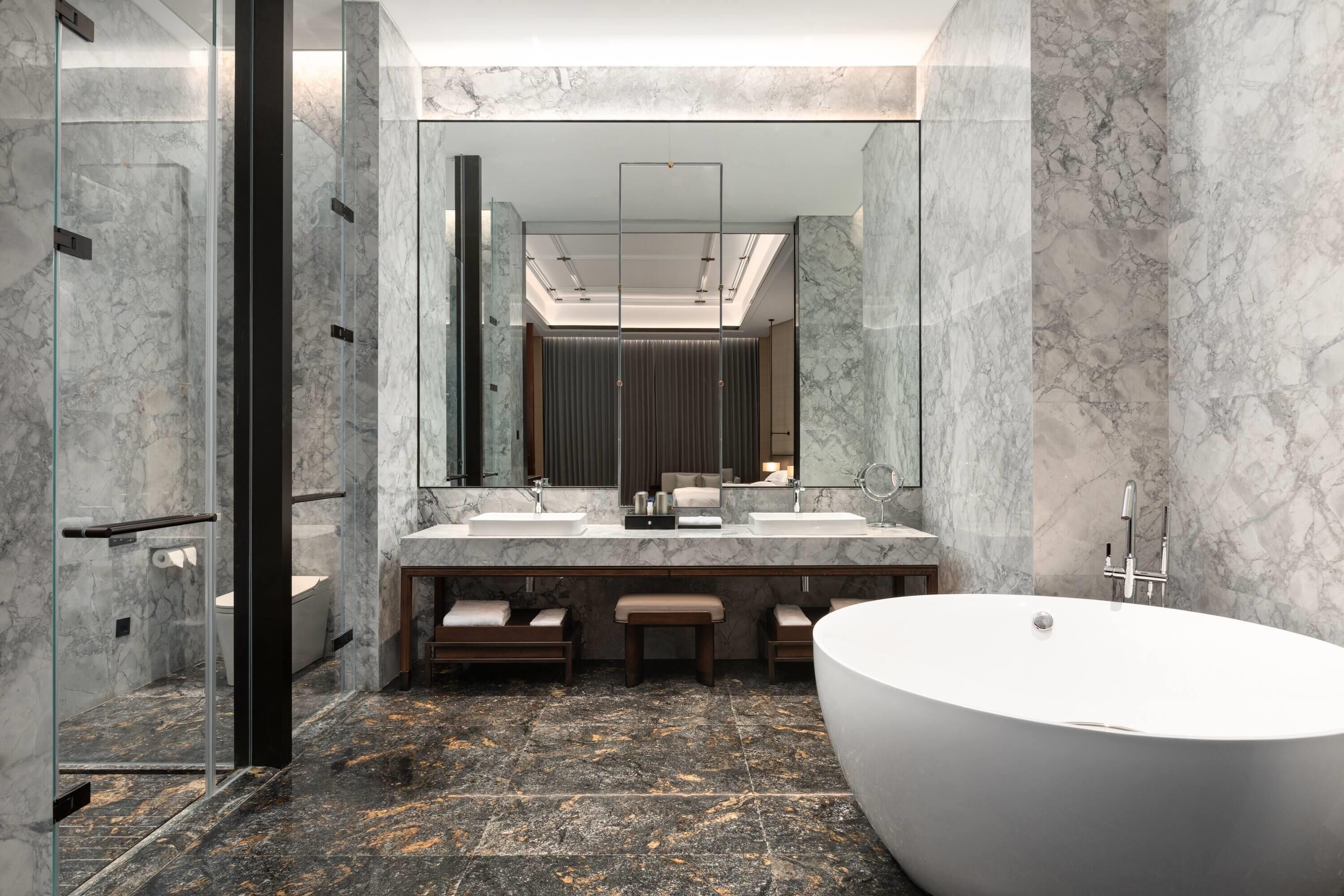 A modern bathroom with a large freestanding bathtub, two sinks, and a large mirror.