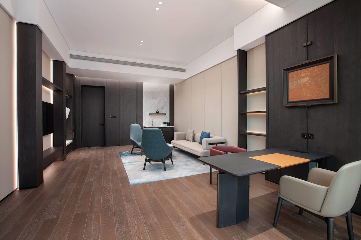 Ein modernes Wohnzimmer mit dunklem Holzboden, einer Couch, einem Esstisch und einem Fernseher.