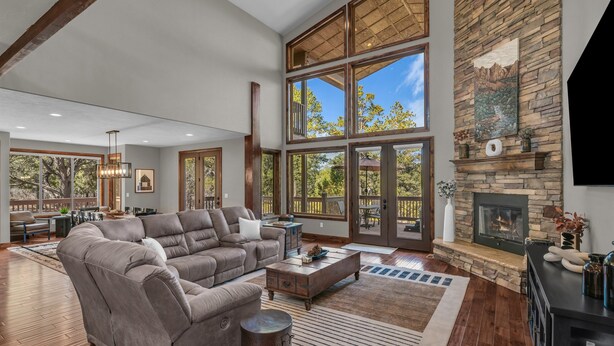 A spacious living room with a large sectional sofa, a fireplace, and large windows offering a view of the outdoors.