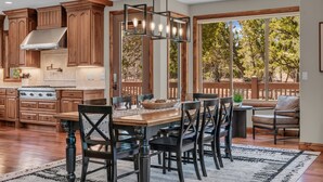 A spacious kitchen with wooden cabinets, a large island, and a dining area with chairs and a table.