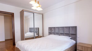 Un dormitorio con una cama de madera, un espejo grande, una mesita de noche y un armario.