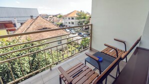 Un balcón con una mesa y sillas, con vistas a una zona residencial con casas y coches aparcados.