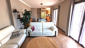 A living room with a white sofa, a round wooden coffee table, and a large plant. - Appt 3 stars, view on bassin de Thau Terr 30 m² Pets accepted (Mèze)