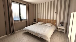 A bedroom with a bed, two bedside tables, a window with curtains, and a striped wall. - Appt 3 stars, view on bassin de Thau Terr 30 m² Pets accepted (Mèze)