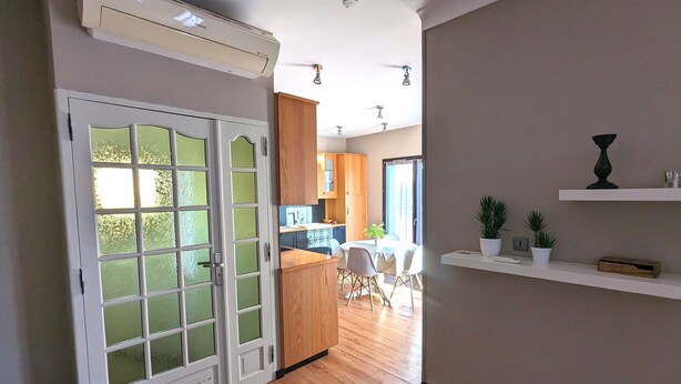 A modern kitchen with wooden cabinets, a dining area with a table and chairs, and a hallway leading to a living space. - Appt 3 stars, view on bassin de Thau Terr 30 m² Pets accepted (Mèze)