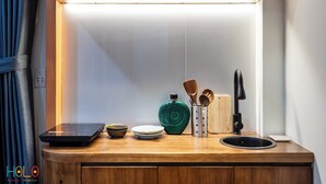 A kitchen counter with a built-in induction cooktop, a green pot, a cutting board, a knife block, and a black electric kettle.