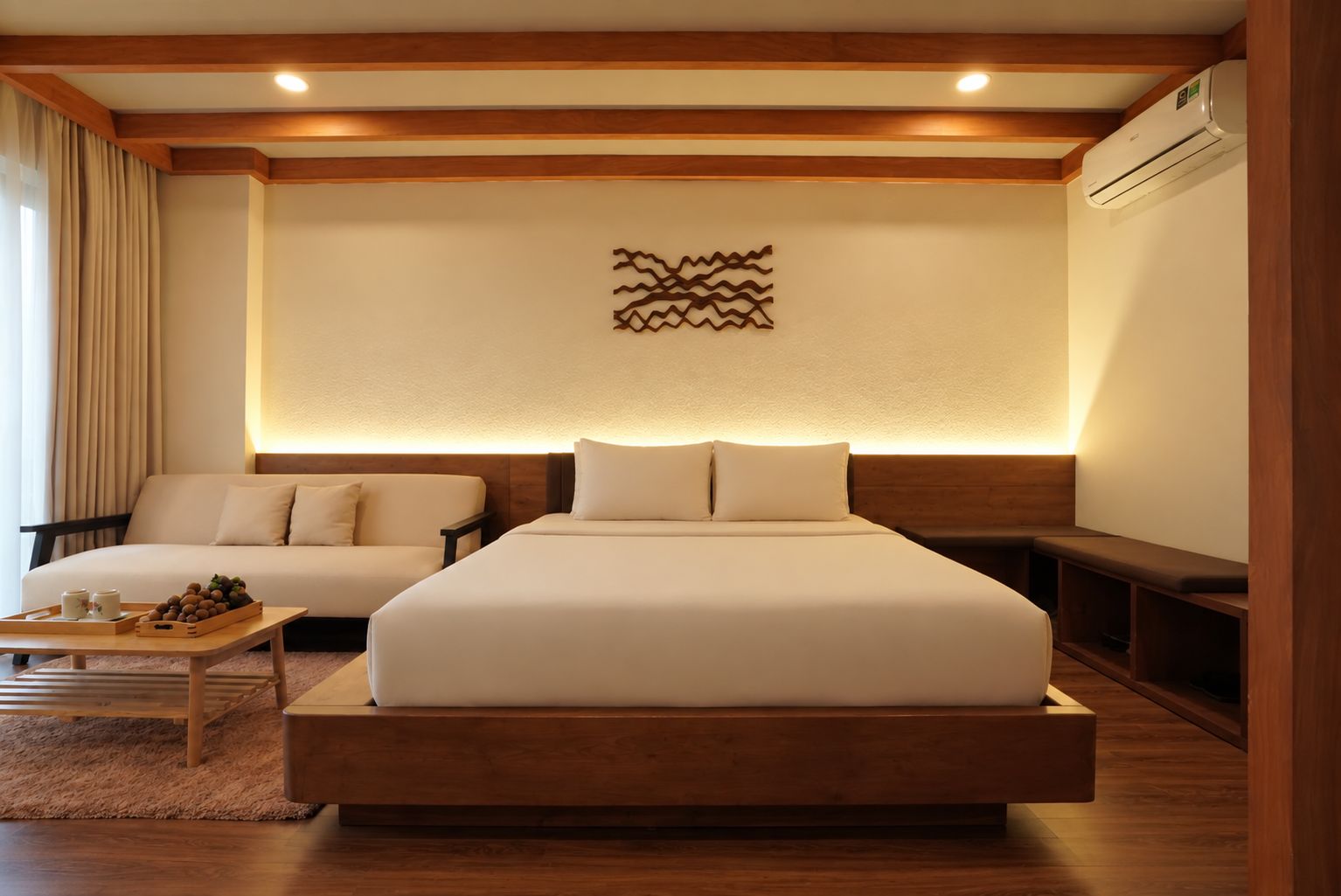 Habitación de hotel con una cama grande, un sofá, una mesa de centro de madera y un aire acondicionado instalado en la pared.