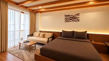 Een moderne hotelkamer met een groot bed, een bank, een klein tafeltje met schaakstukken en een decoratief wandobject.