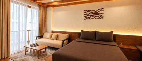 A modern hotel room with a large bed, a sofa, a small table with chess pieces, and a decorative wall piece.