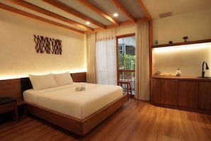 Una camera d'albergo con un letto grande, una testiera in legno, una piccola scrivania e un balcone con tende.